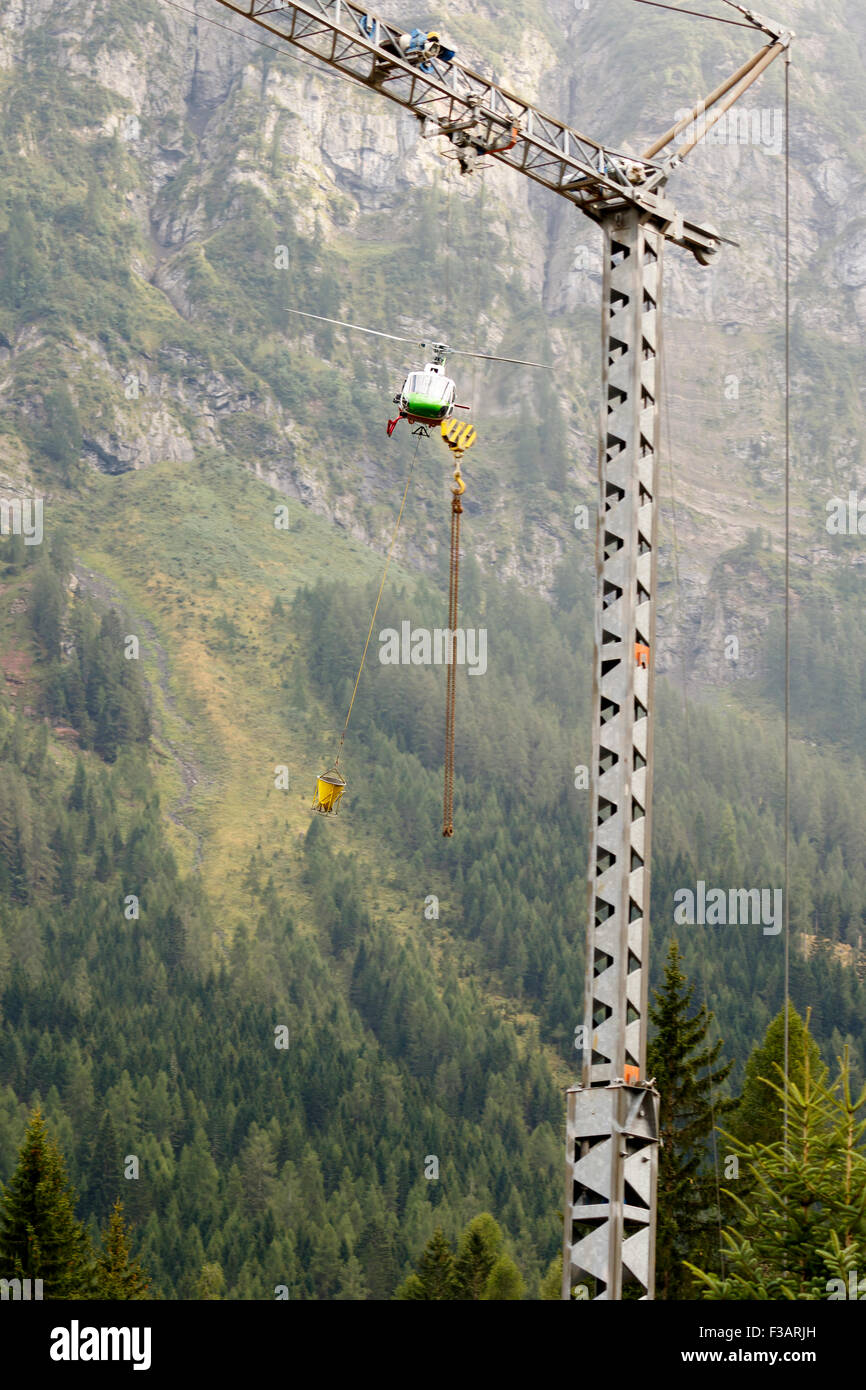 Falcade, Belluno, Italia - 21 agosto 2015: trasporto elicottero fornisce materiale per un sito in costruzione in montagna Foto Stock