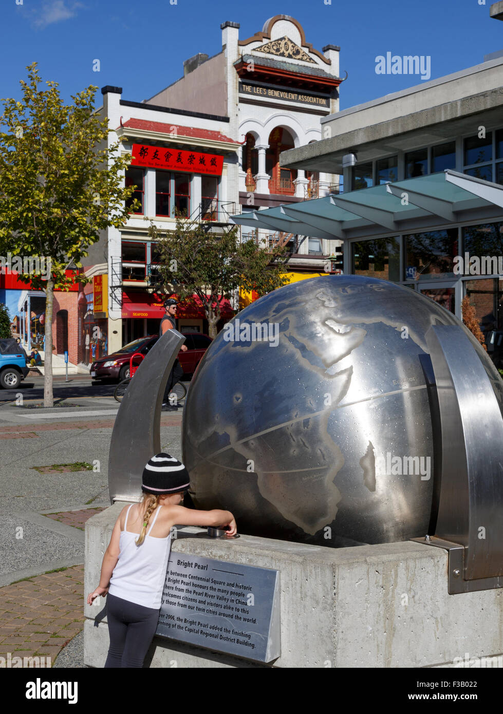 Ragazza alla perla brillante interattivo di un acciaio in movimento globe situato tra Piazza del Centenario e Chinatown Victoria Vancouver Island British Columbia Foto Stock
