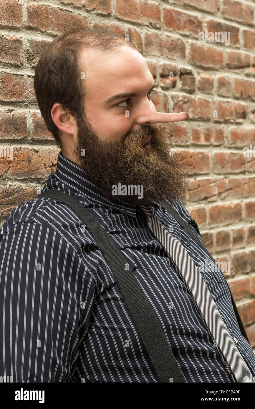 Ben vestito giacente uomo barbuto abbagliamenti maliziosamente Foto Stock