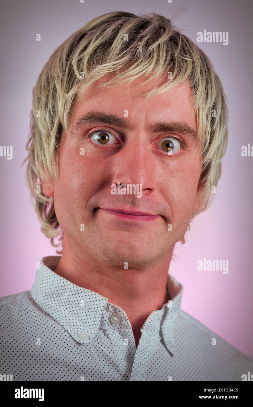 Grinning sciocco uomo con capelli biondi e occhi grandi Foto Stock