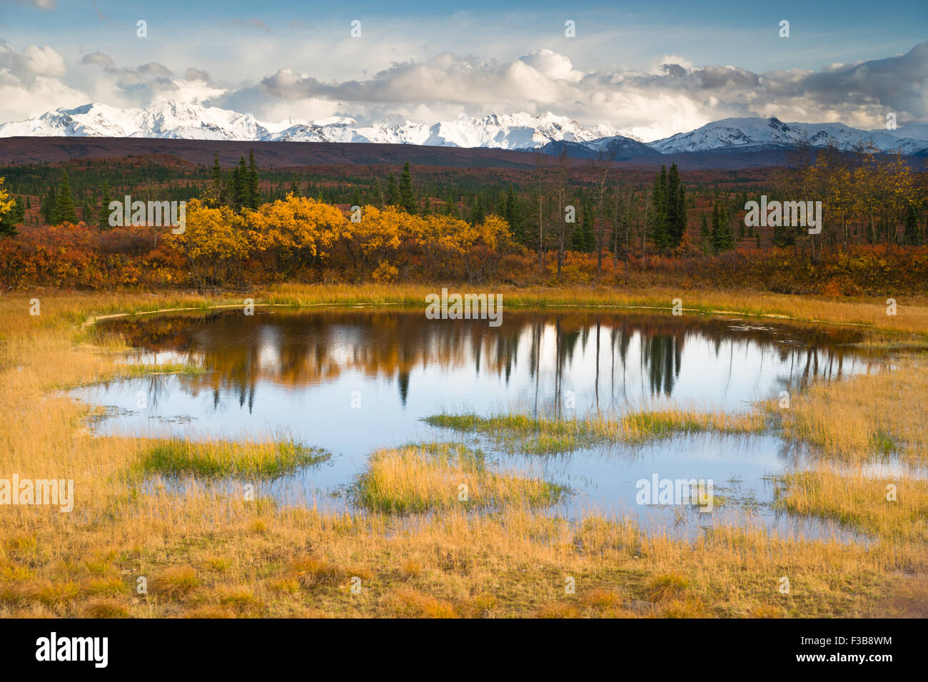 Il sole pigoli attraverso un poco nuvoloso cielo alla luce l'Alaska Range Foto Stock