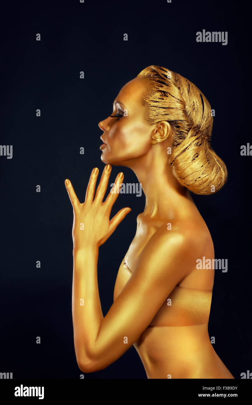 Donna con corpo dorato su sfondo nero Foto Stock