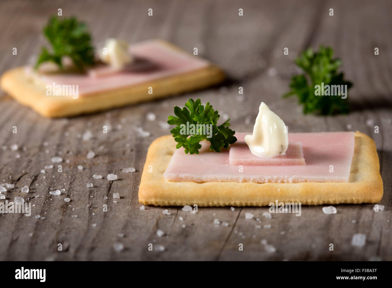 Crackers con prosciutto e salsa roumulade sul legno scuro piano portapaziente con il prezzemolo e il sale Foto Stock