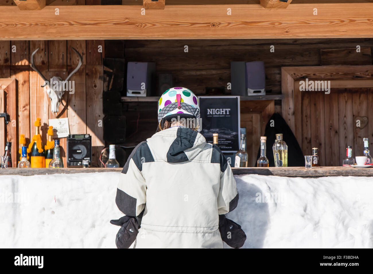 Vista posteriore della donna sciatori con casco in attesa presso il Mountain Lodge contatore per un drink Foto Stock