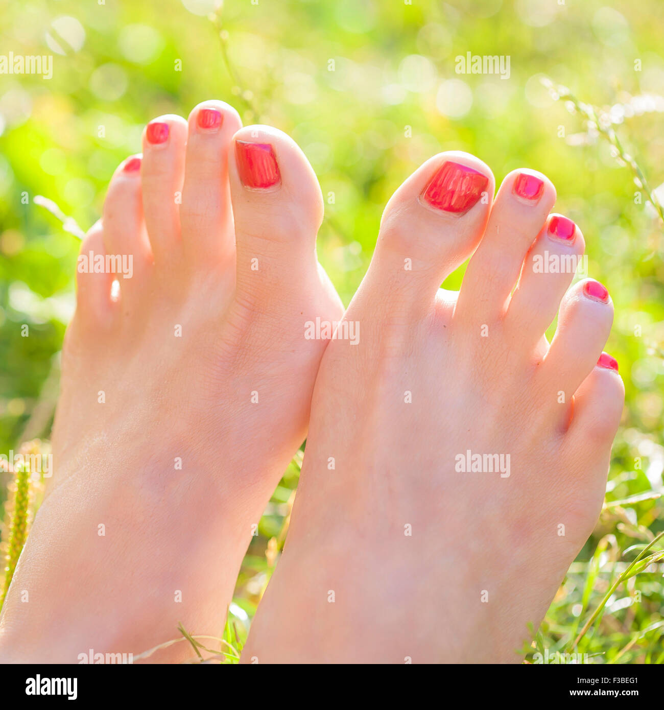 A piedi nudi femminili in erba con rosso smalto per unghie Foto stock -  Alamy