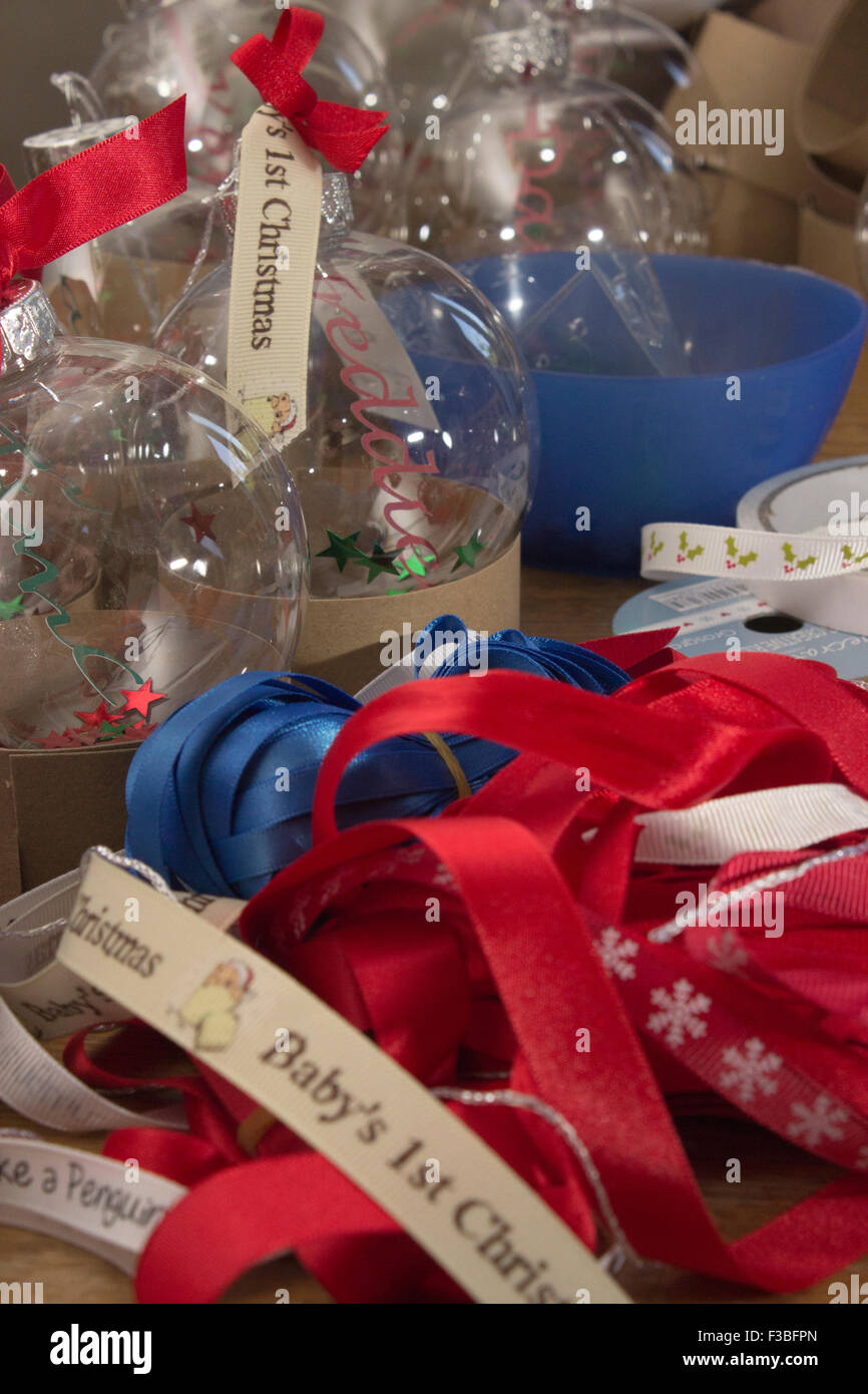 Prepararsi al Natale con baubles e nastro rosso archi, glittery stelle e oro stringa. Divertimento natalizio su una tabella di artigianato. Foto Stock