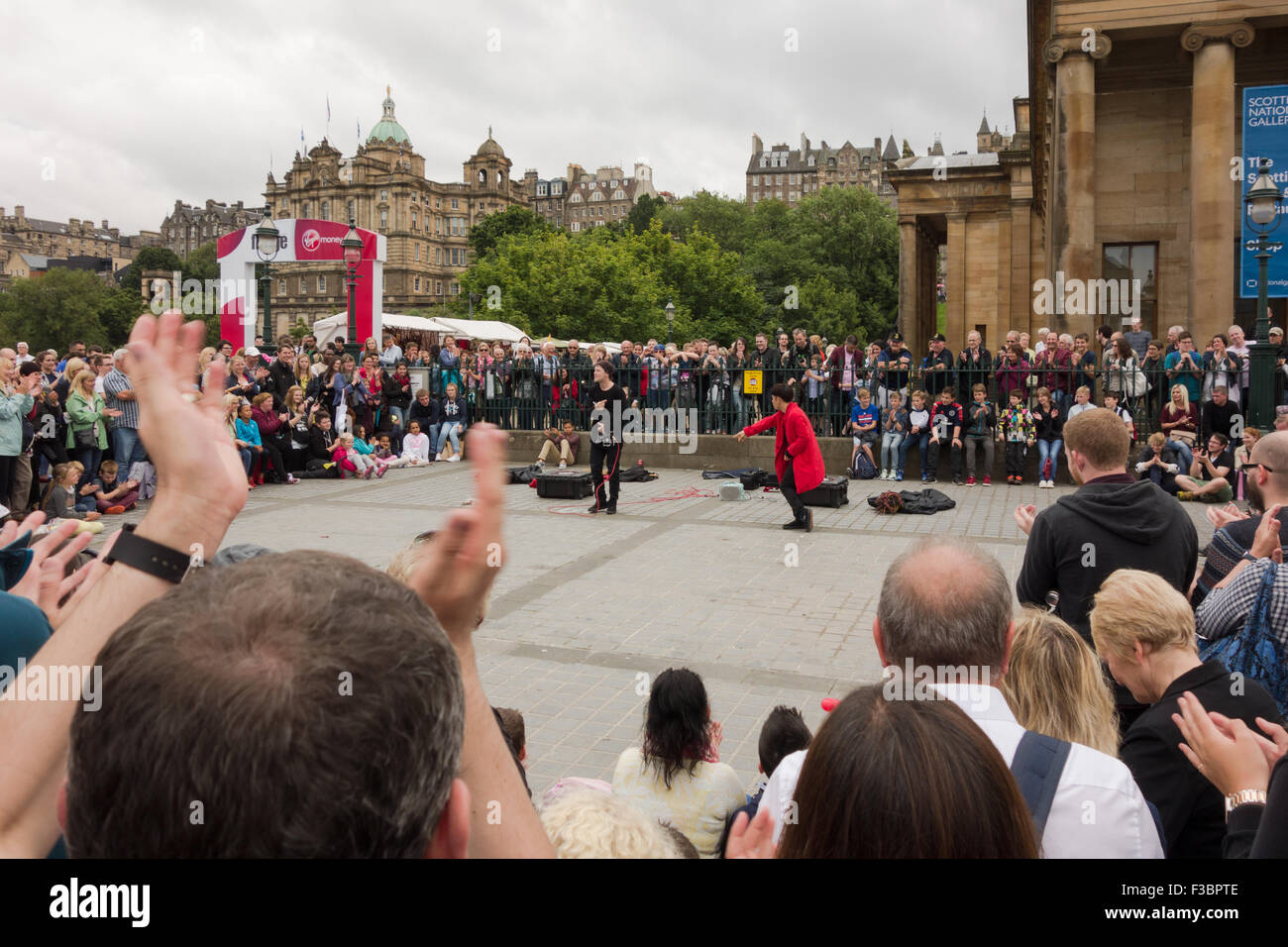 La folla godendo di Edinburgh Fringe Festival 2015 agire "Funny ossa Cestino' al di fuori della Scottish National Gallery Foto Stock