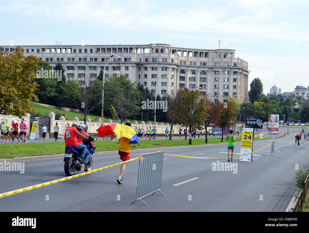 Bucarest, Romania - 4 ottobre 2015: un atleta nel 2015 Bucarest Maratona Internazionale sventola la bandiera rumena come egli corre giù Calea 13 Septembrie e attrae l'interesse della moto troupe. Più di 10.000 atleti di tutte le abilità ha preso parte alla giornata di eventi. Credito: Douglas MacKenzie/Alamy Live News Foto Stock
