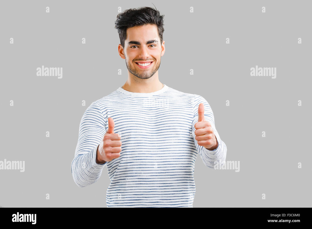 Ritratto di bel giovane con il pollice in alto, isolate su uno sfondo grigio Foto Stock