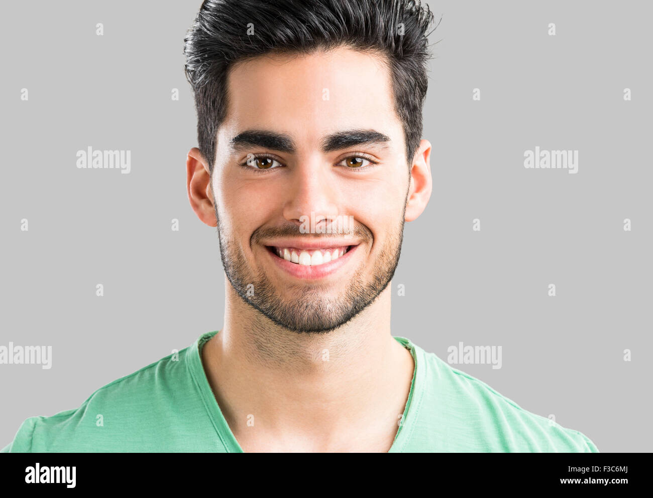 Ritratto di bel giovane uomo sorridente, isolata su uno sfondo grigio Foto Stock