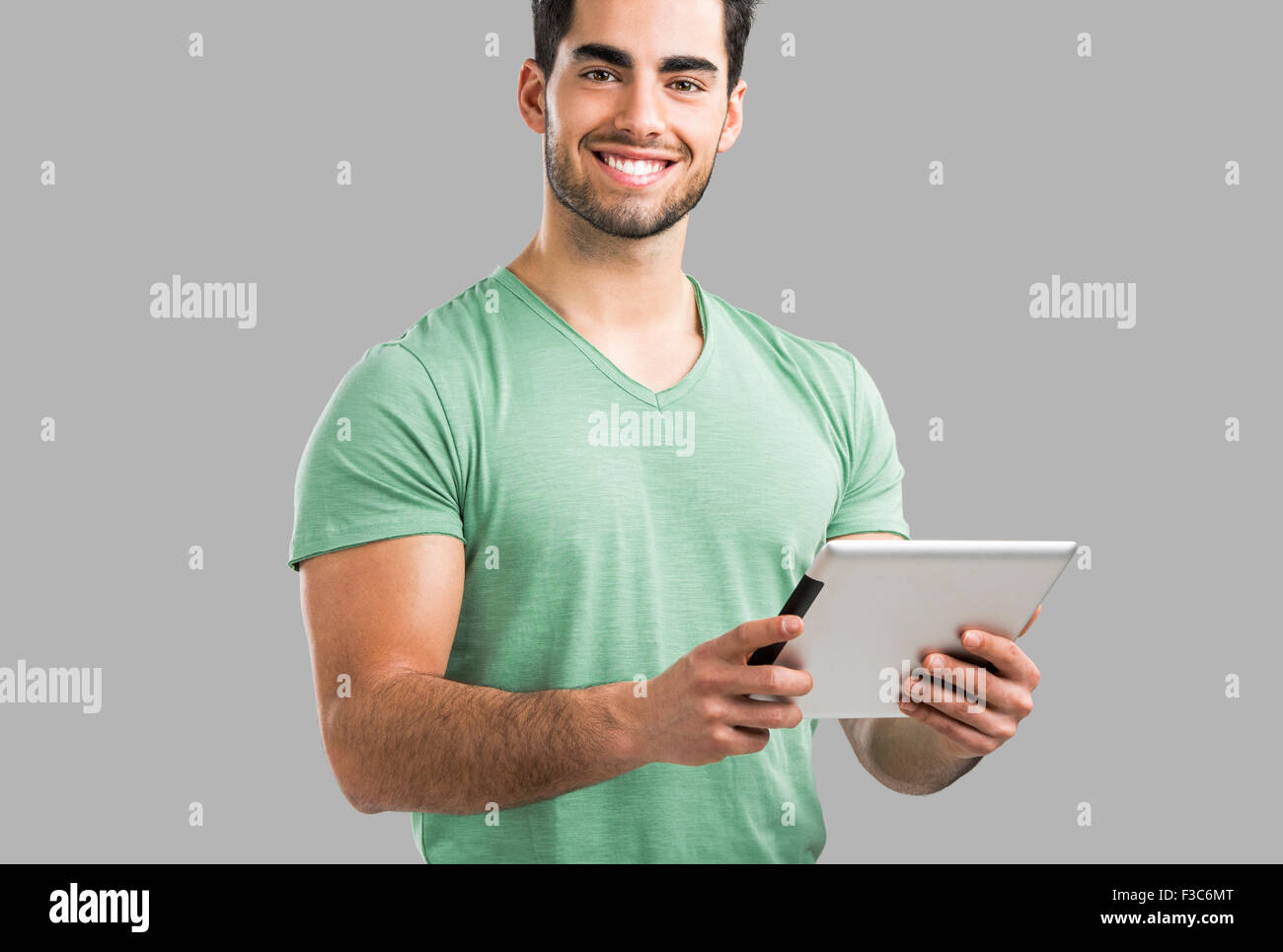 Bel giovane uomo che lavora con una pastiglia, isolate su uno sfondo grigio Foto Stock