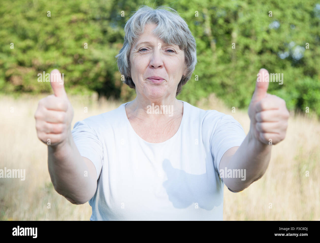 La vecchiaia donna mostra Thumbs up con entrambe le mani Foto Stock