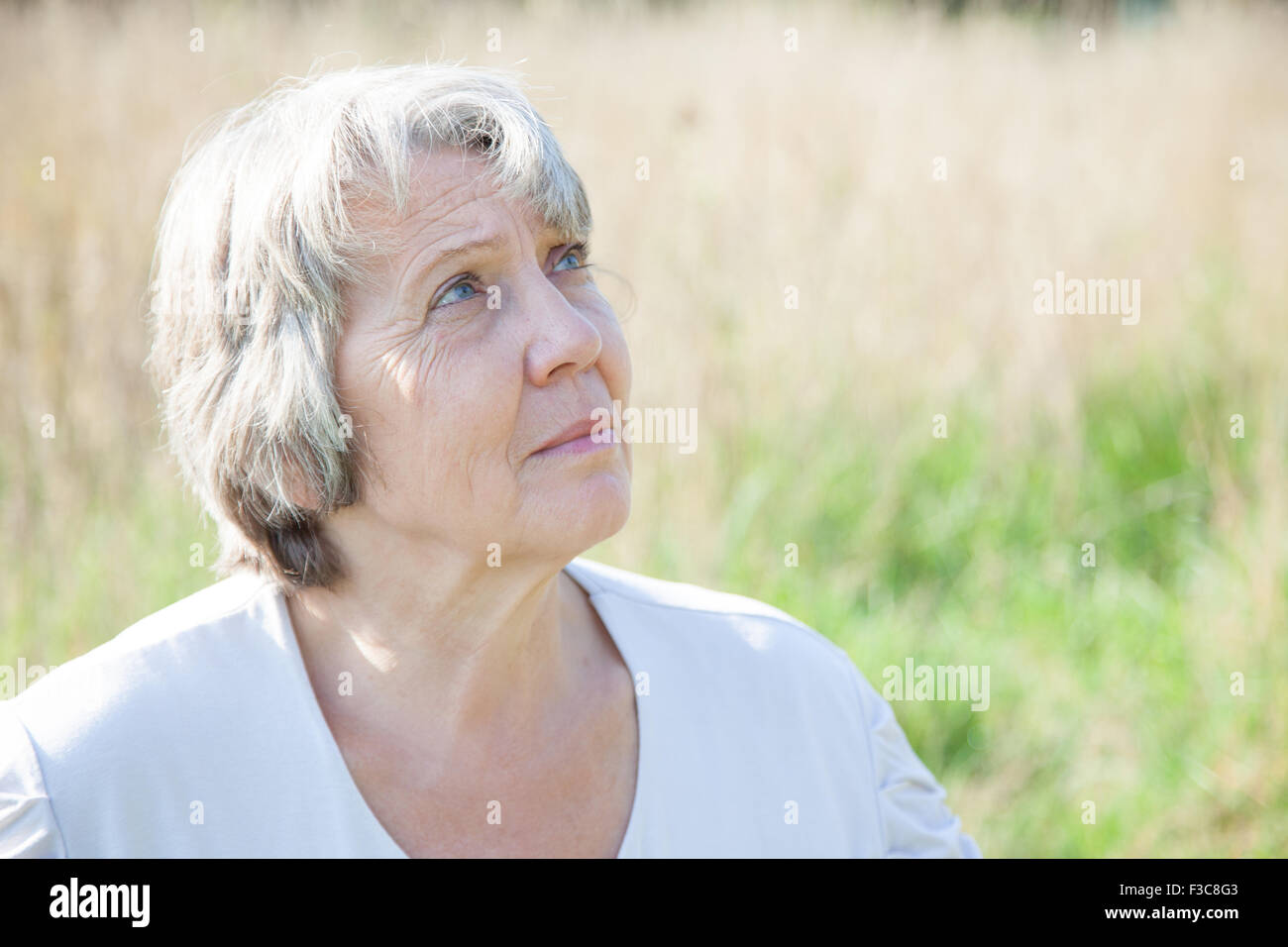 La vecchiaia donna che guarda verso l'alto Foto Stock