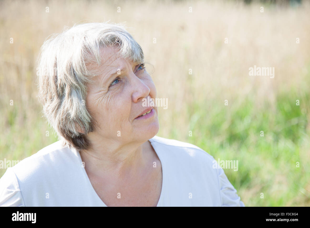 La vecchiaia donna che guarda verso l'alto mentre essendo esterno Foto Stock