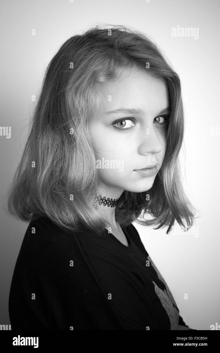 Bella bionda caucasica ragazza adolescente in nero. Studio in bianco e nero ritratto su sfondo bianco con ombra morbida Foto Stock