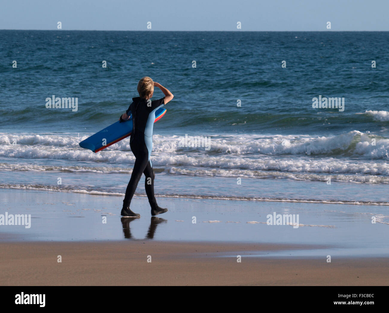 Donna di mezza età voce per il mare con un bodyboard, Cornwall, Regno Unito Foto Stock