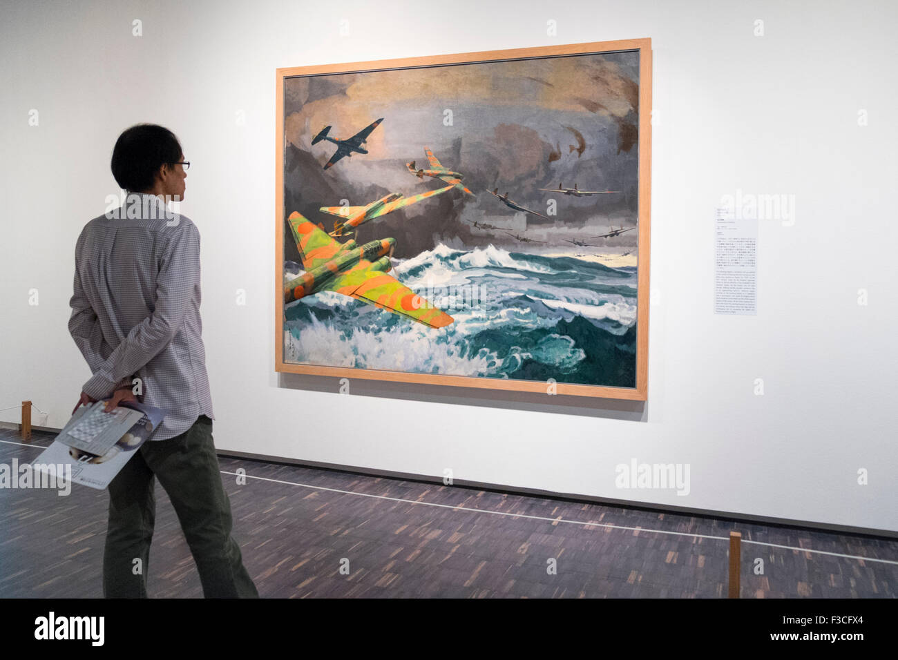 Uomo che guarda un dipinto bombardamenti transoceanico da Toraji Ishikawa presso il Museo Nazionale di Arte Moderna di Tokyo Foto Stock