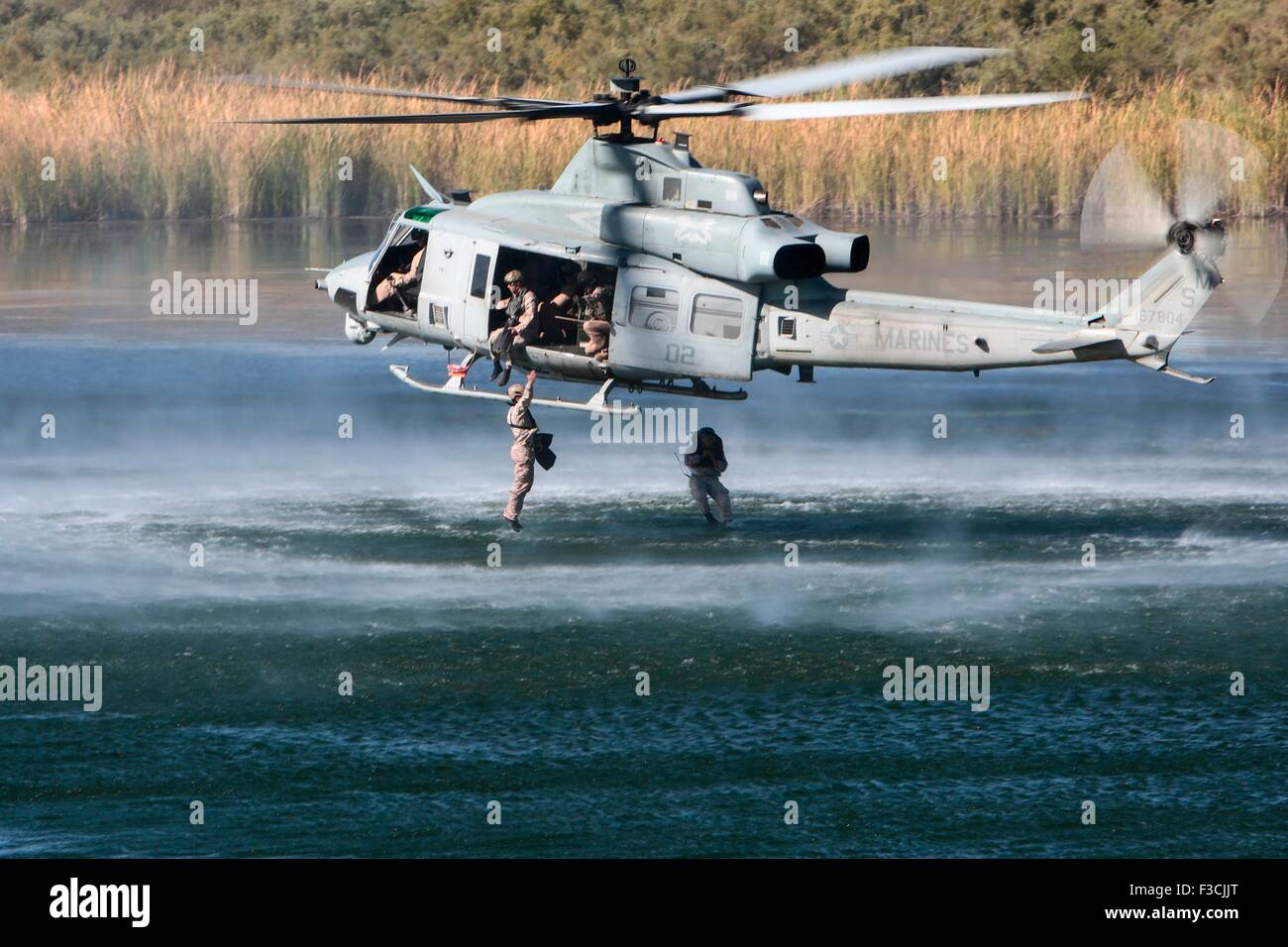 US Marine delle forze speciali commandos con forza di 1 società di ricognizione, saltare da un UH-1Y Venom elicottero nel lago Ferguson durante l'inserimento della formazione chiamato helocasting Ottobre 3, 2015 vicino a Yuma, Arizona. Foto Stock