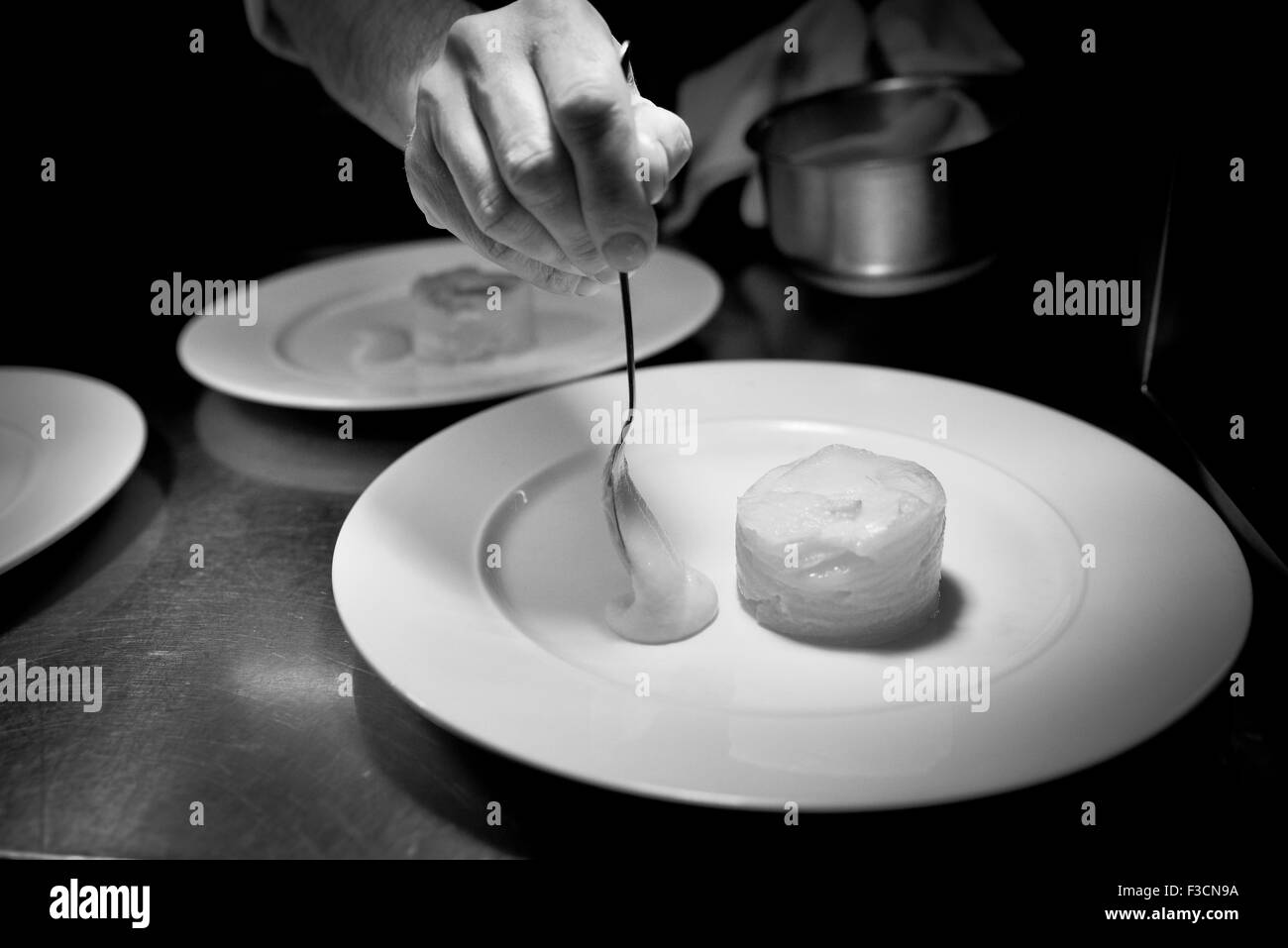 Lo Chef disponendo il cibo sulla piastra per la presentazione ottimale Foto Stock