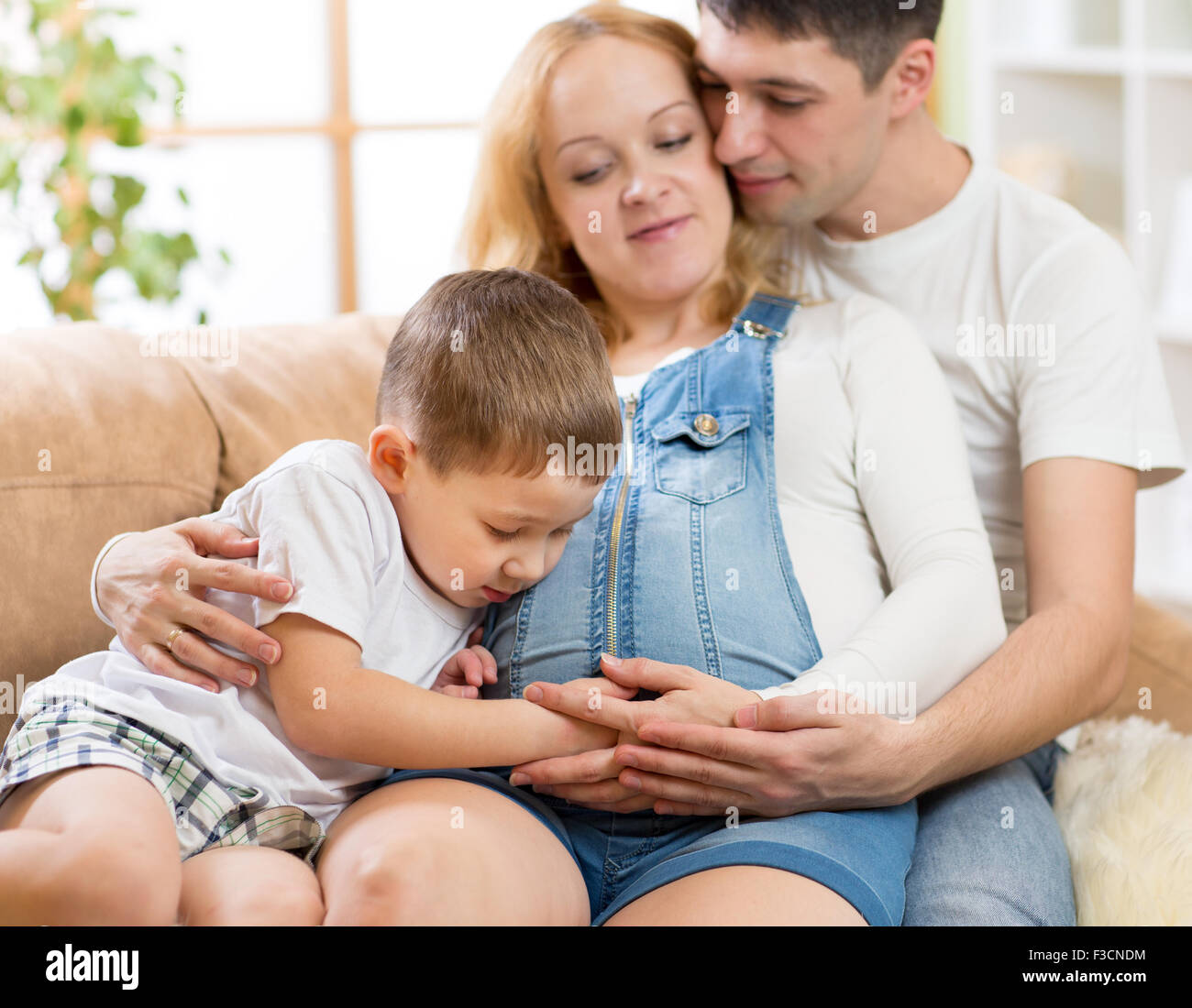 Famiglia aspettano di nuovo bambino. Little Boy toccando donna incinta pancia Foto Stock