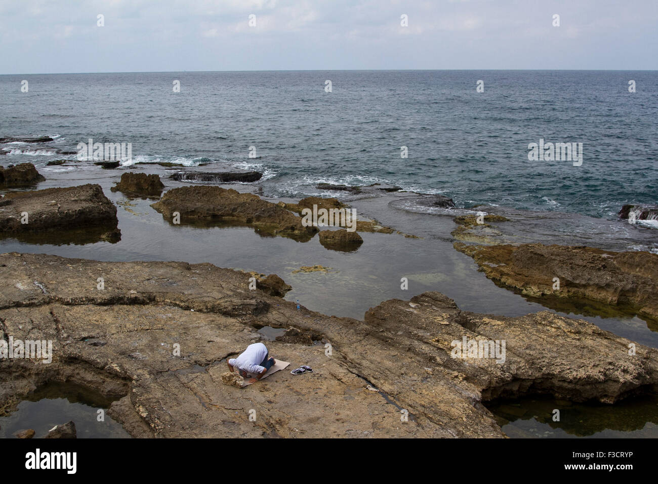 Beirut Libano 2015. Ott 2015. Un uomo trova un posto sulle rocce costiere fuori Beirut shore per eseguire la preghiera islamica rituale (Salat AL Zuhr) al credito midda: amer ghazzal/Alamy Live News Foto Stock