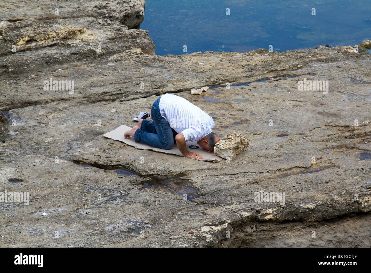 Beirut Libano 2015. Ott 2015. Un uomo trova un posto sulle rocce costiere fuori Beirut shore per eseguire la preghiera islamica rituale (Salat Al Zuhr) al credito midda: amer ghazzal/Alamy Live News Foto Stock