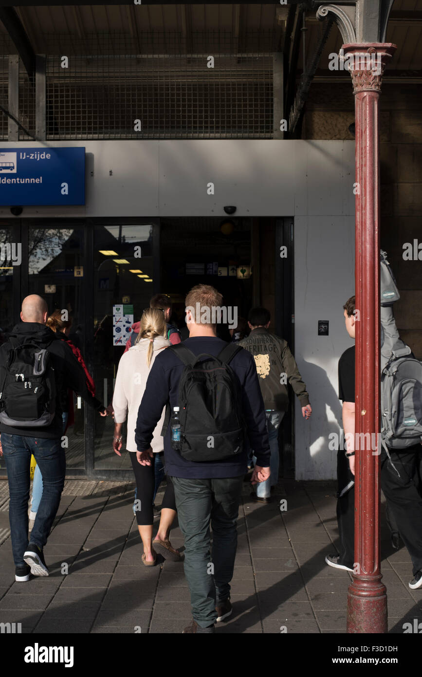 I viaggiatori casuali immettendo la Stazione Centrale di Amsterdam, con segno di Amsterdam sulla stazione parzialmente visibile (Ingresso Est) Foto Stock