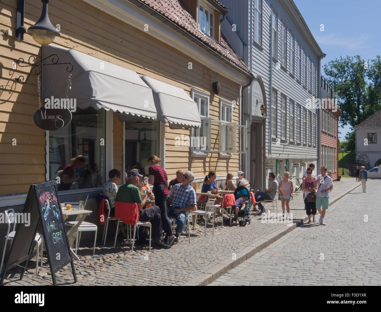 Idilliaco street con le tradizionali case in legno, café e in estate gli ospiti il relax sul marciapiede, Gamlebyen Fredrikstad Norvegia Foto Stock
