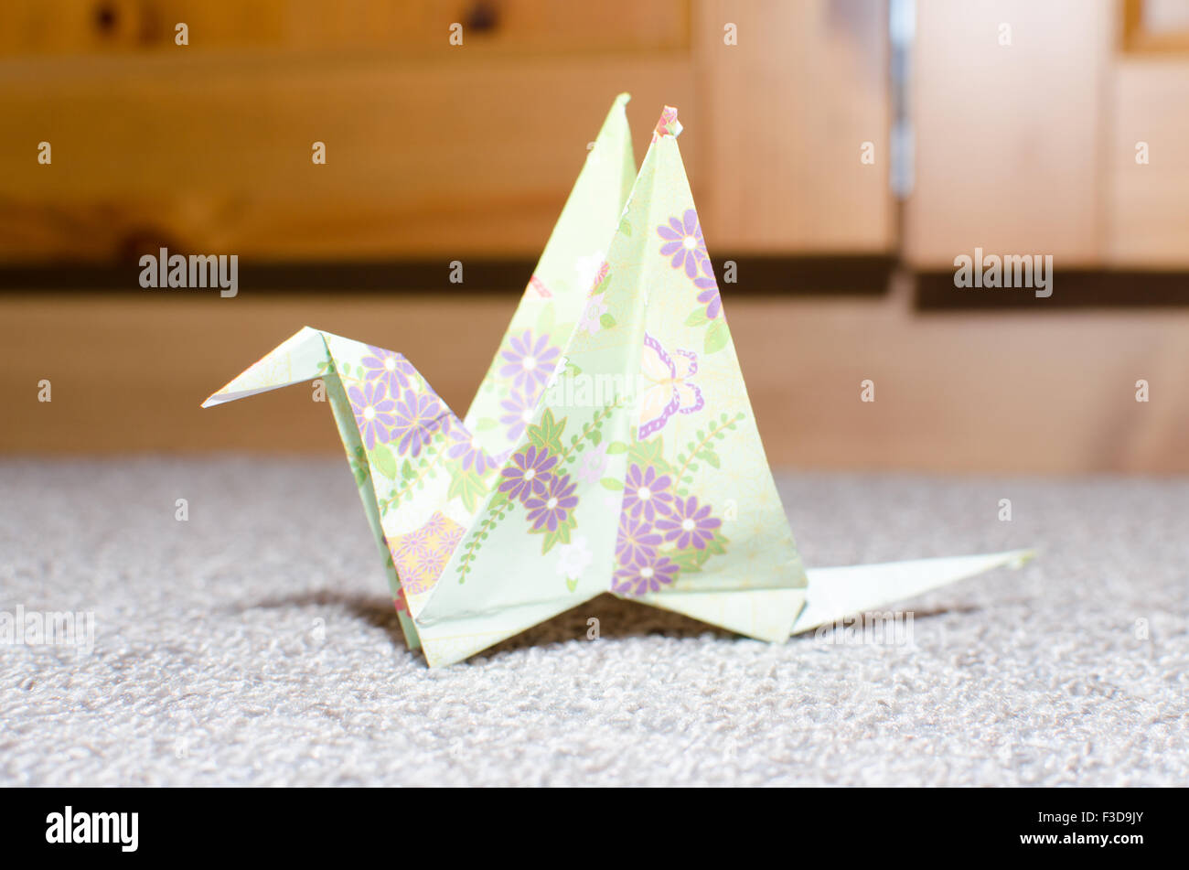 Una piegatura della carta, origami di un uccello closeup su un tappeto grigio Foto Stock