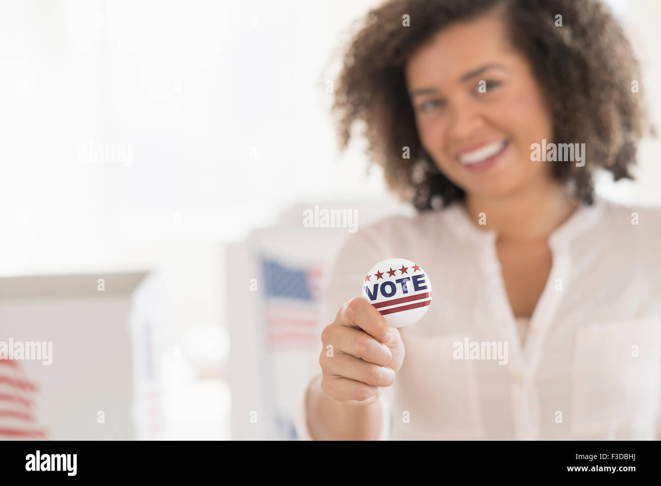 Giovane donna azienda badge di voto e sorridente Foto Stock