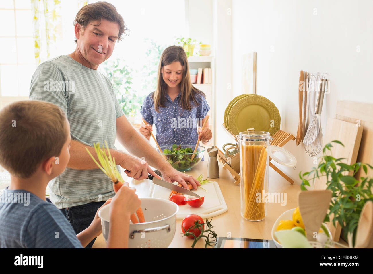 Bambini (8-9, 10-11) preparare il cibo con il loro padre Foto Stock