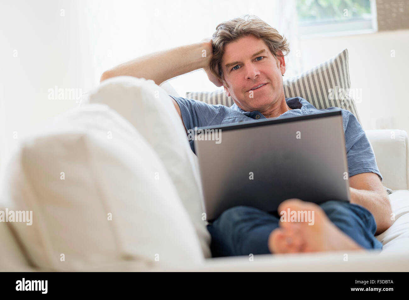 Uomo maturo utilizzando computer portatile sul divano Foto Stock