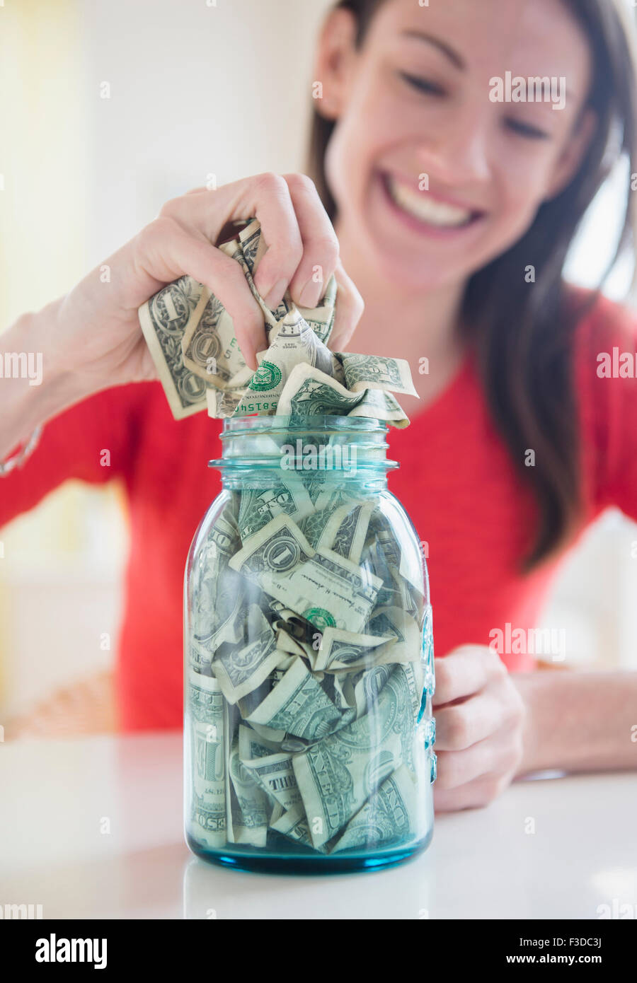 Donna mettendo i soldi in vaso Foto Stock