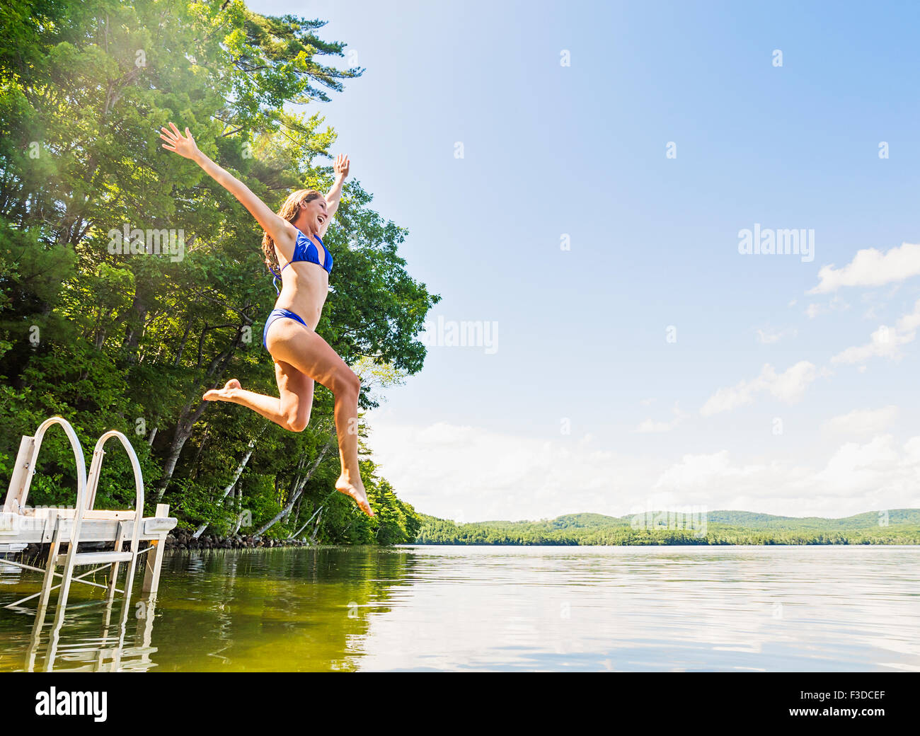 Giovane donna che si tuffa nel lago dal jetty Foto Stock