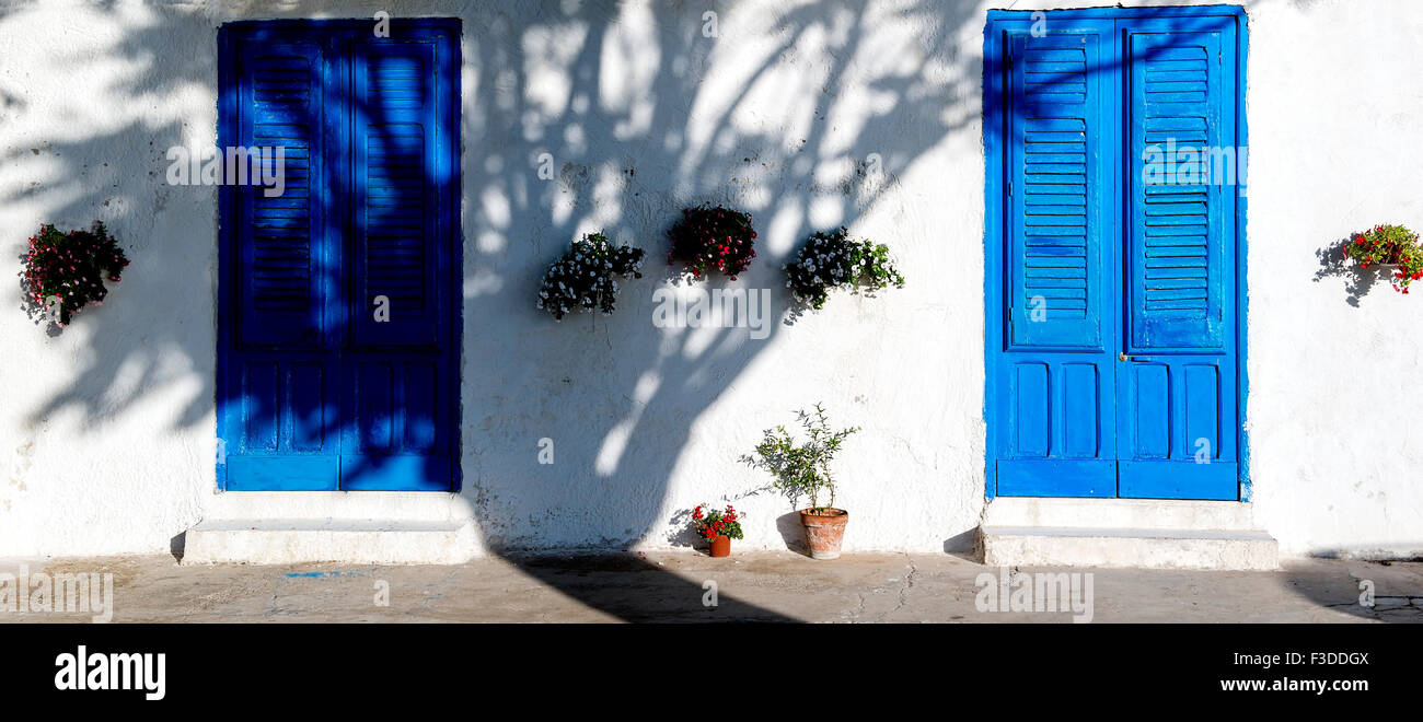 Tipico e blu iconica porta in legno chiaro contro il muro bianco nella luce del tramonto Foto Stock