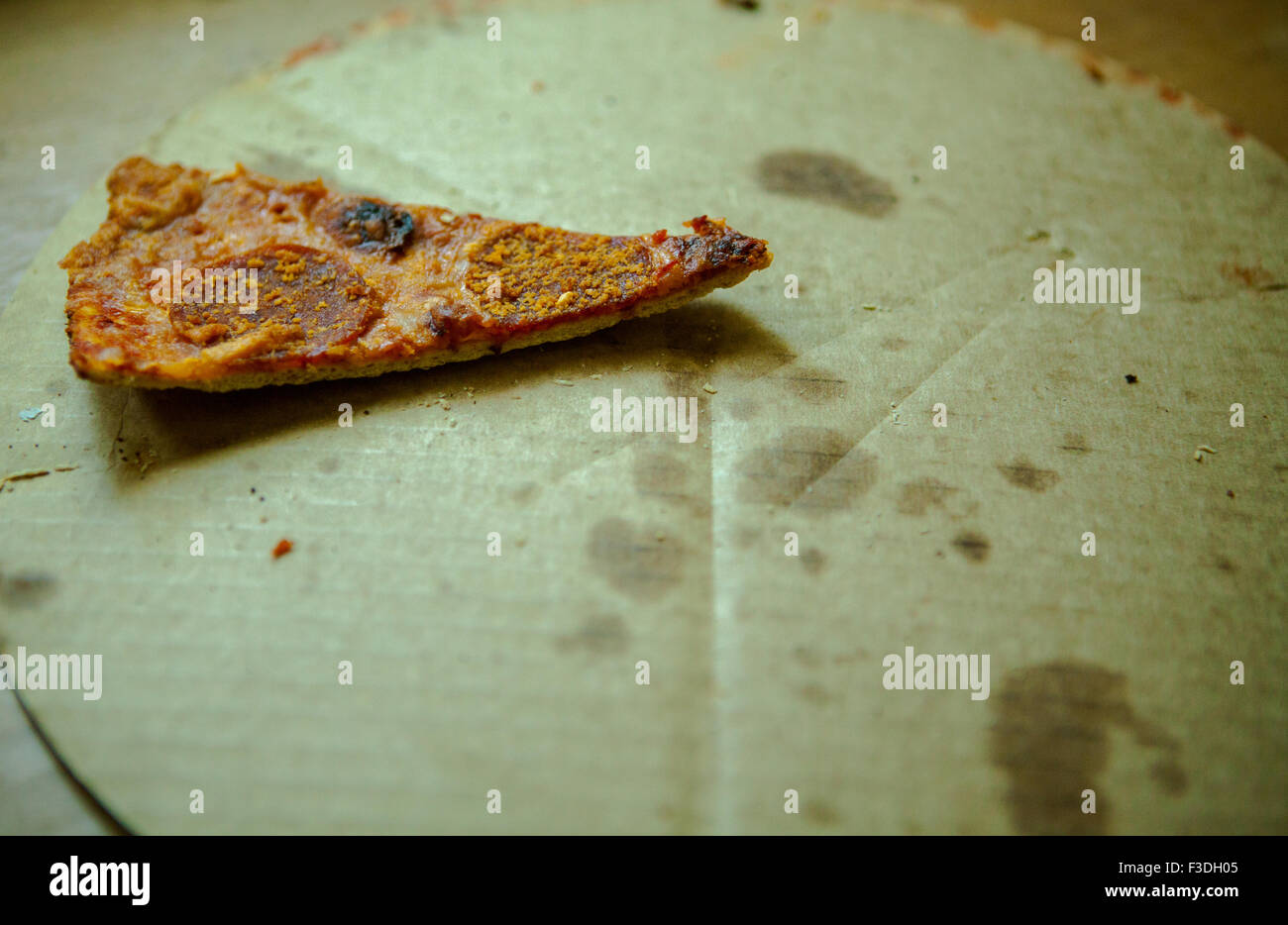 Singola fetta di avanzi di salsiccia per pizza pizza su cartone Foto Stock