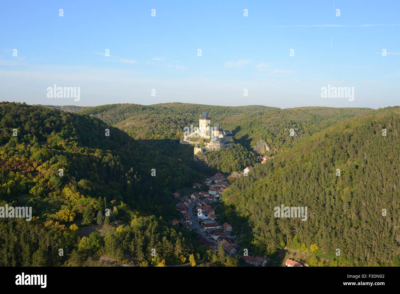 VISTA AEREA. Castello di Karlstejn che domina la città mercato dello stesso nome sul fondo valle. Boemia, Repubblica Ceca. Foto Stock