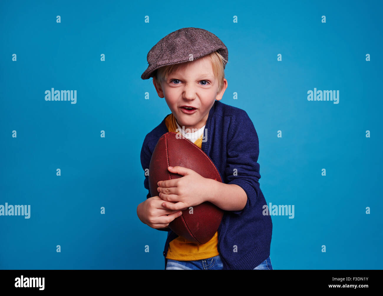 Little Boy con il rugby palla su sfondo blu Foto Stock