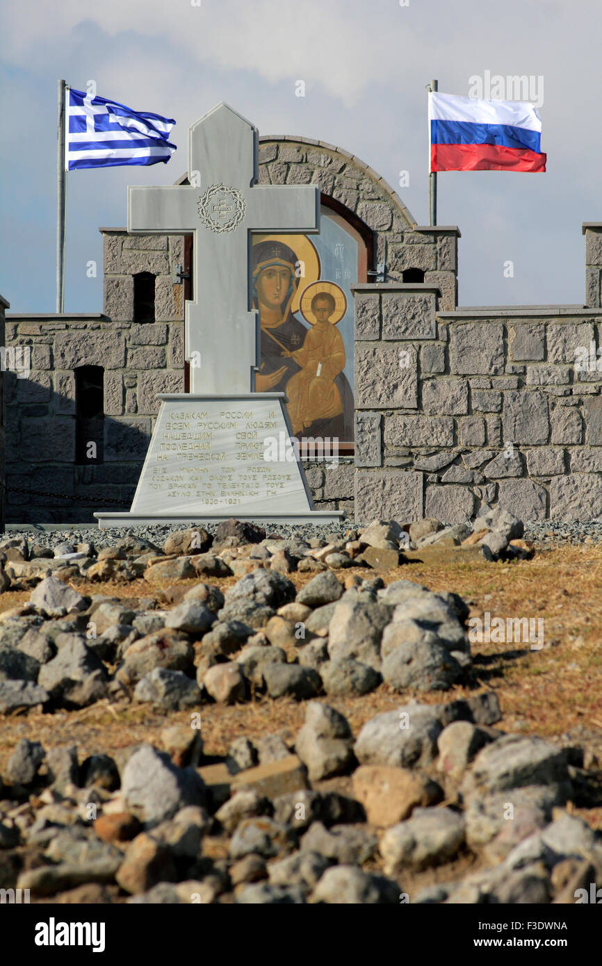 Vista ravvicinata del memorial Russian-Kozak circondato da una pietra-parete realizzata con le bandiere sventolano.Cape Punta. Villaggio Pesperago, Limnos Foto Stock