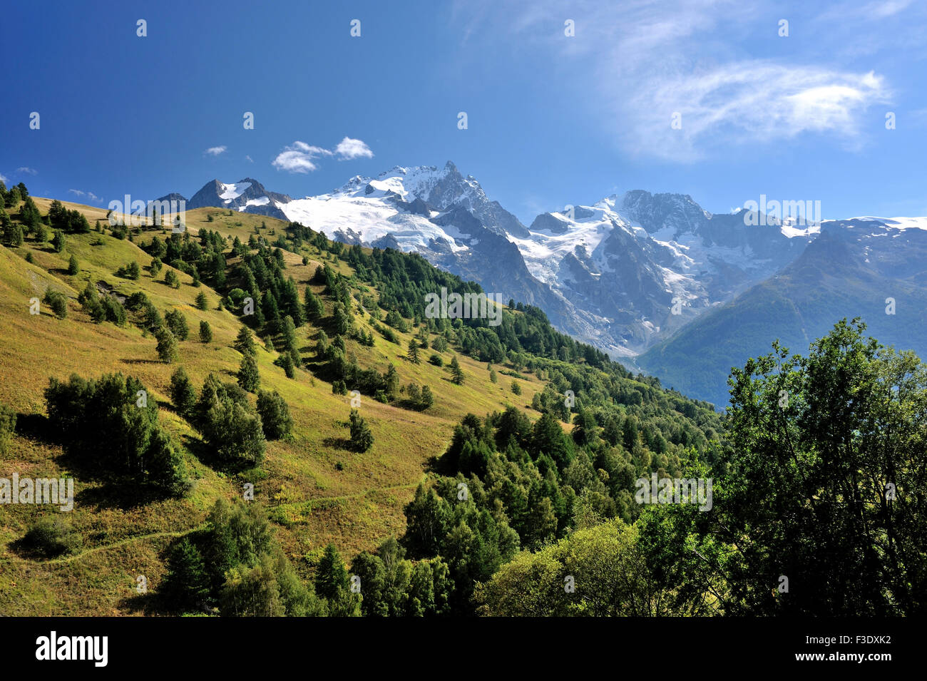 Il paesaggio alpino con il verde delle colline e montagne dalle vette innevate, sulle Alpi francesi, Francia Foto Stock
