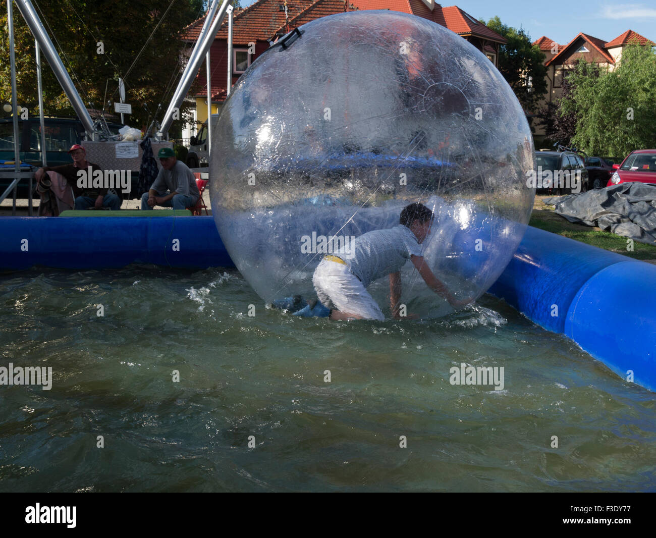 Giovane uomo che cerca di stare in piedi acqua gonfiabile bubble ball Polonia in piscina Foto Stock