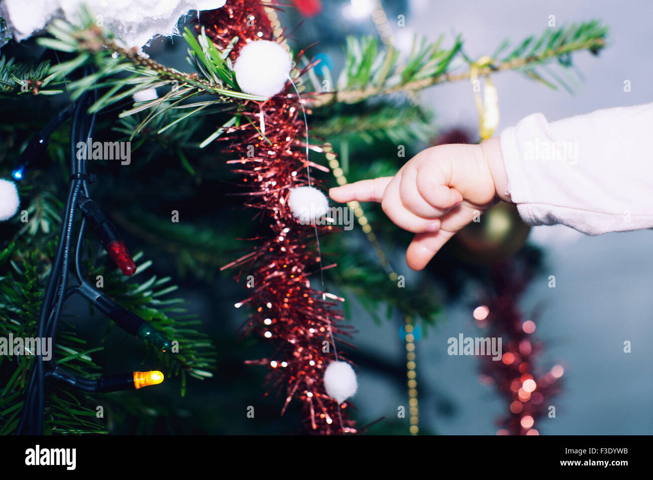 Baby girl toccando le decorazioni su albero di Natale Foto Stock