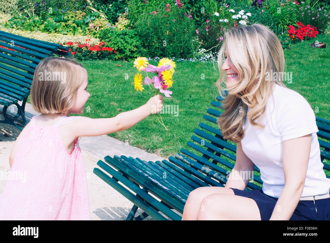 Bambina dando a sua madre un mazzo di fiori in posizione di parcheggio Foto Stock