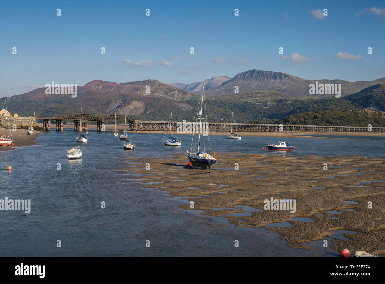 Nel tardo pomeriggio sole illumina una vista di Barmouth harbour con il vecchio ponte della ferrovia e cader Idris gamme della montagna nella distanza. Foto Stock