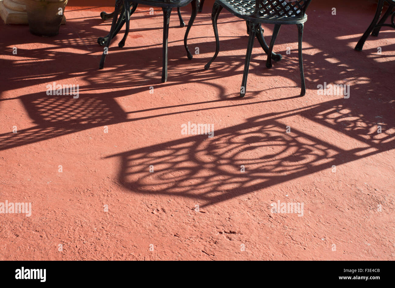 Ombre lunghe di sedie colati in condizioni di luce solare intensa su un balcone che si affaccia sul mare in gioco Larga sull'isola Repubblica di Cuba Foto Stock