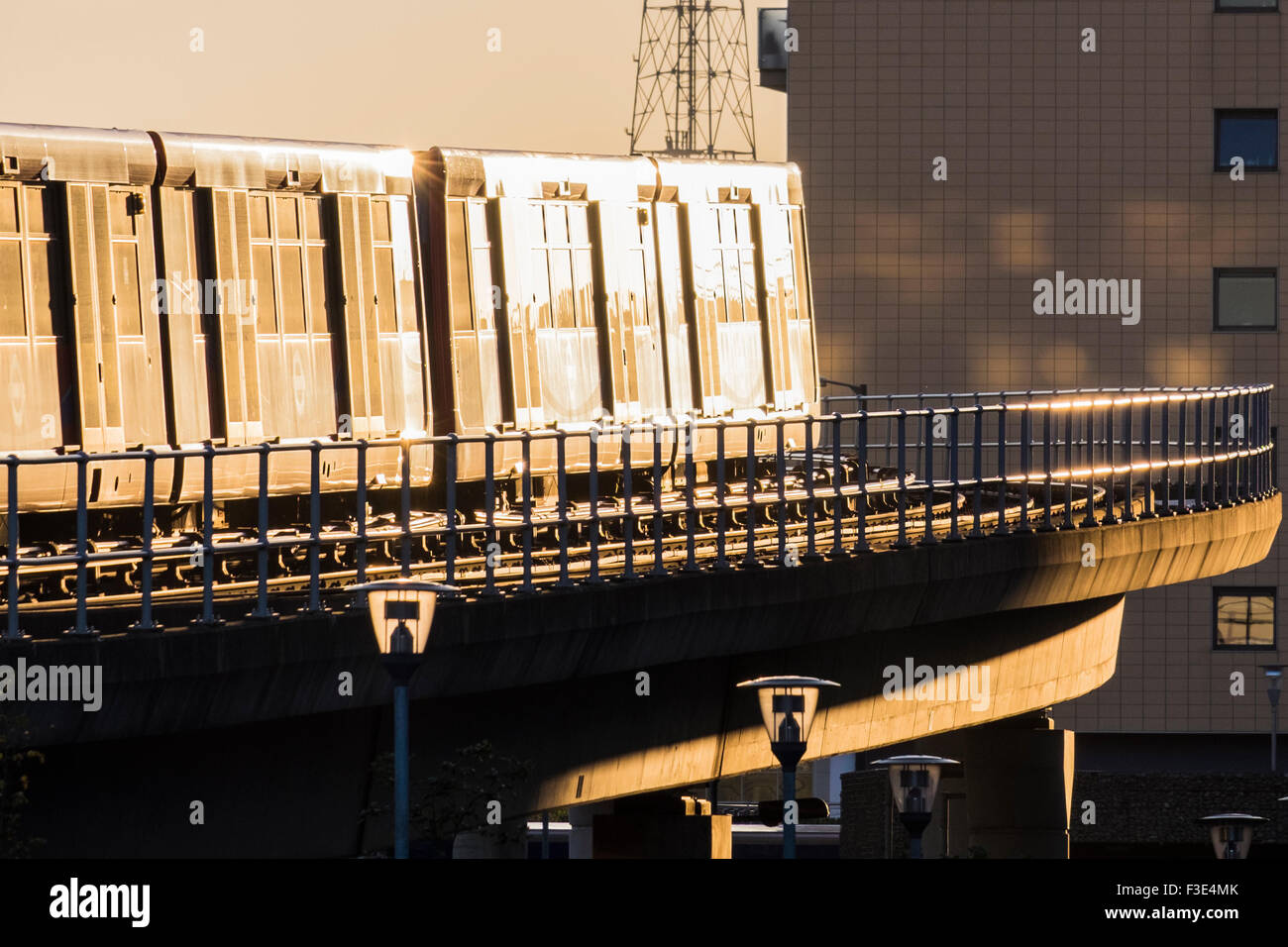 Docklands Light Railway treno illuminato da sunrise, London, England, Regno Unito Foto Stock