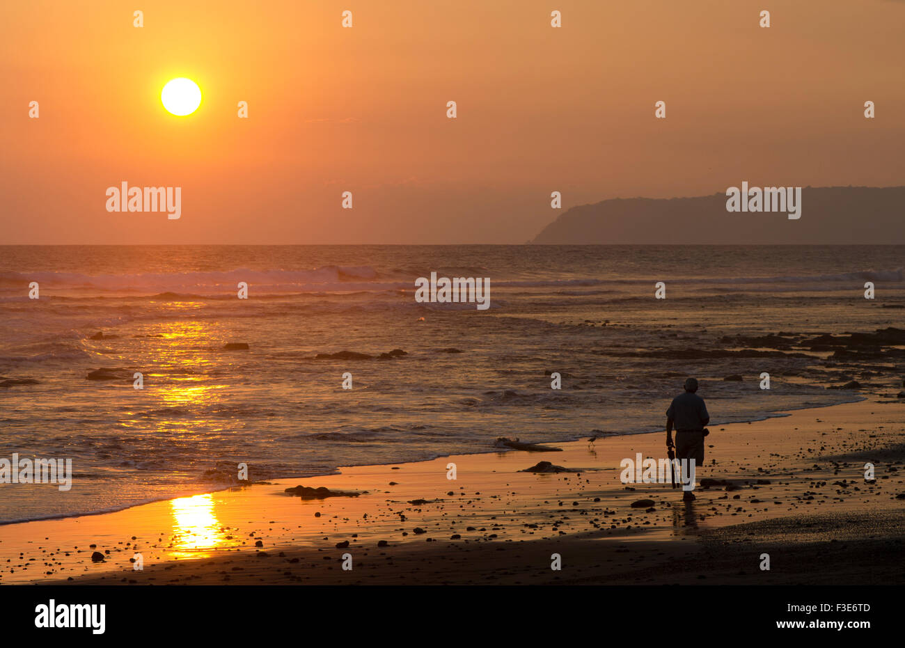 Un uomo che cammina lungo una spiaggia durante il tramonto in Costa Rica. Foto Stock