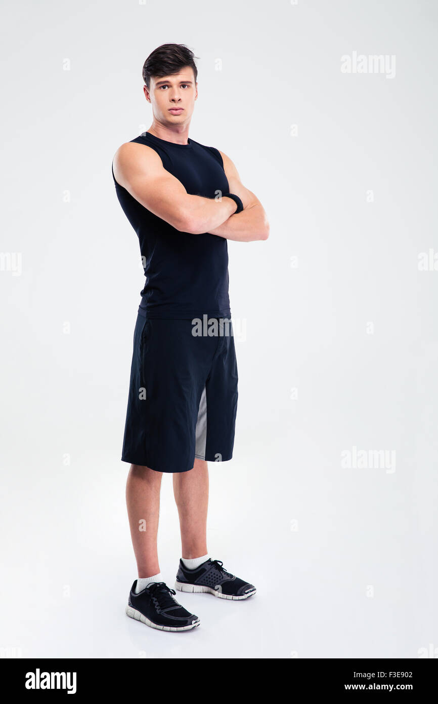 A piena lunghezza Ritratto di un fitness gravi uomo in piedi con le braccia incrociate isolato su uno sfondo bianco e guardando la fotocamera Foto Stock