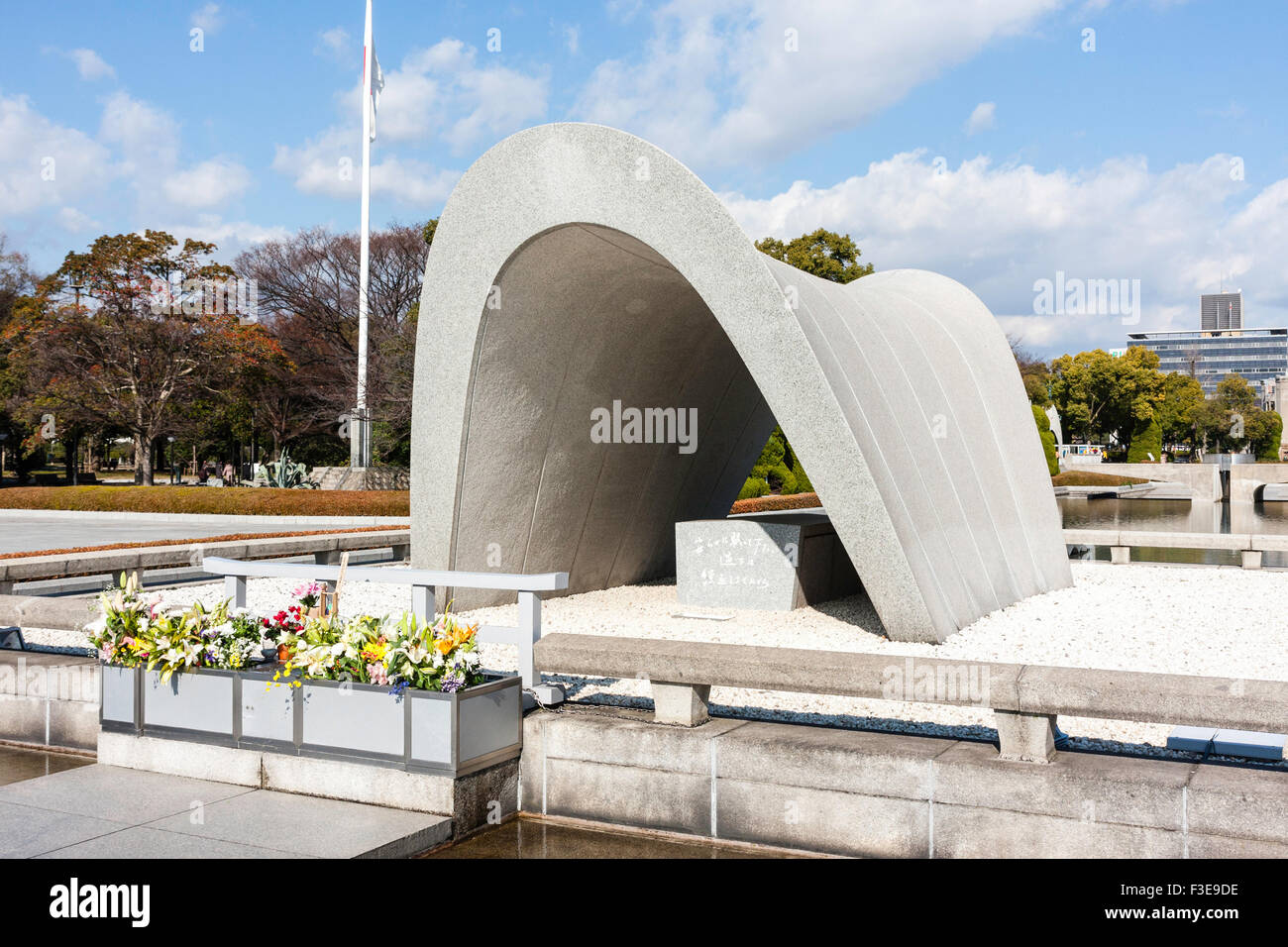 Hiroshima, Giappone, il Parco della Pace. Il cenotafio di curve per la bomba a vittime, con la fiamma della pace in background al di sotto di un inverno cielo blu. Foto Stock