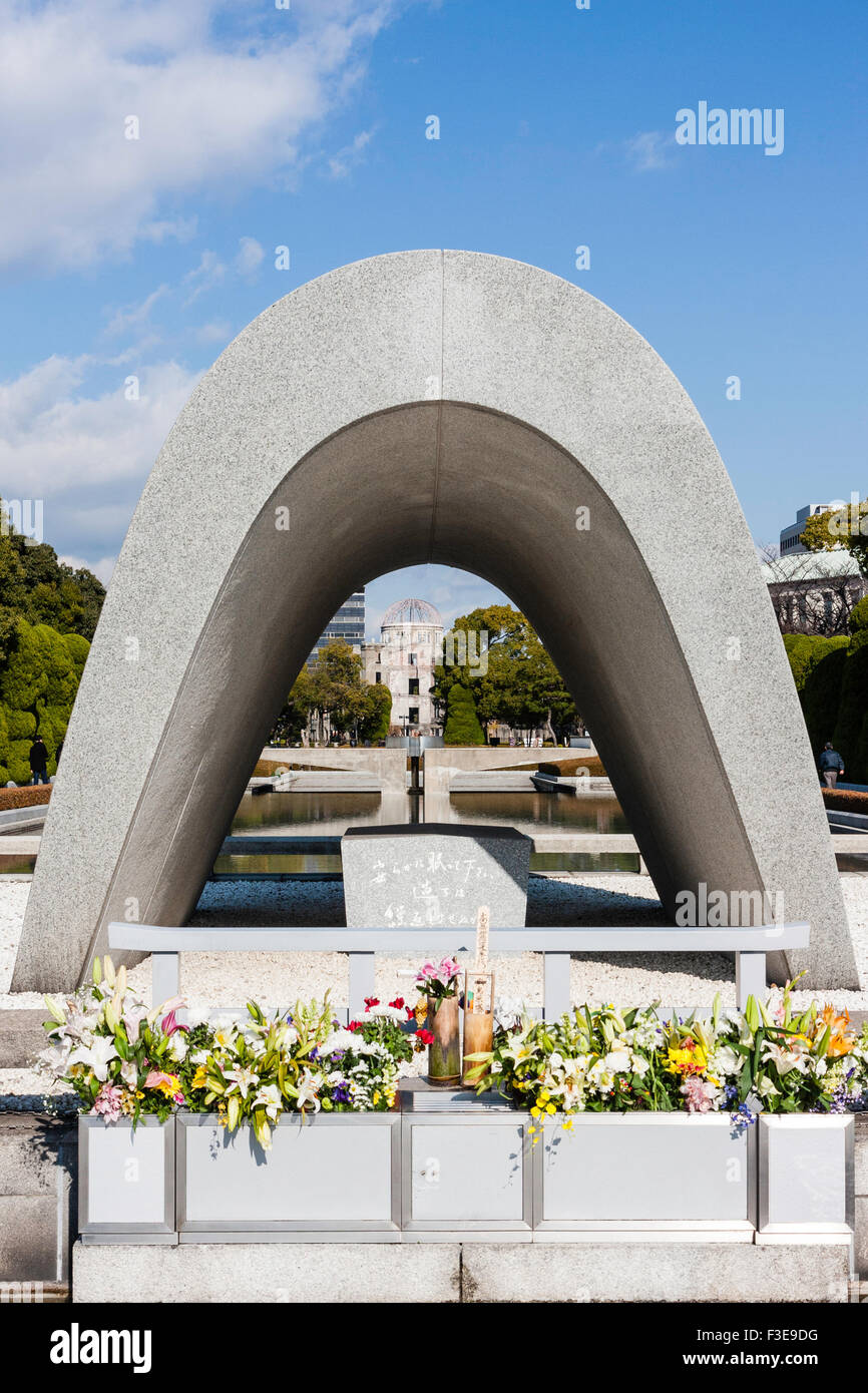 Hiroshima, Giappone, il Parco della Pace. Il cenotafio, con la fiamma della pace al di là che le rovine di una cupola della bomba sotto l'inverno cielo blu. Foto Stock